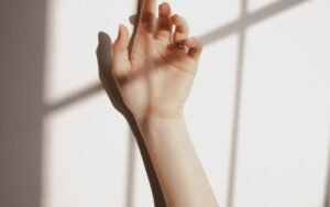 Hand held near a sunlit wall with soft shadows