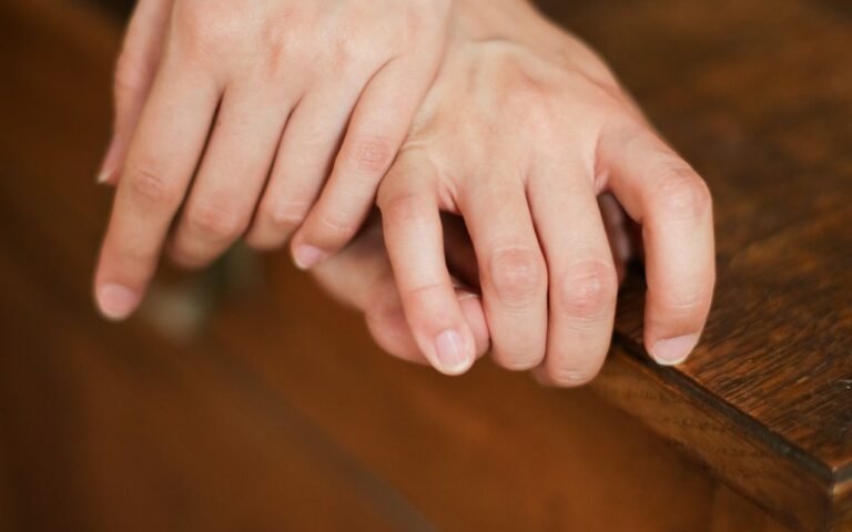 Hands resting on the edge of a wooden table