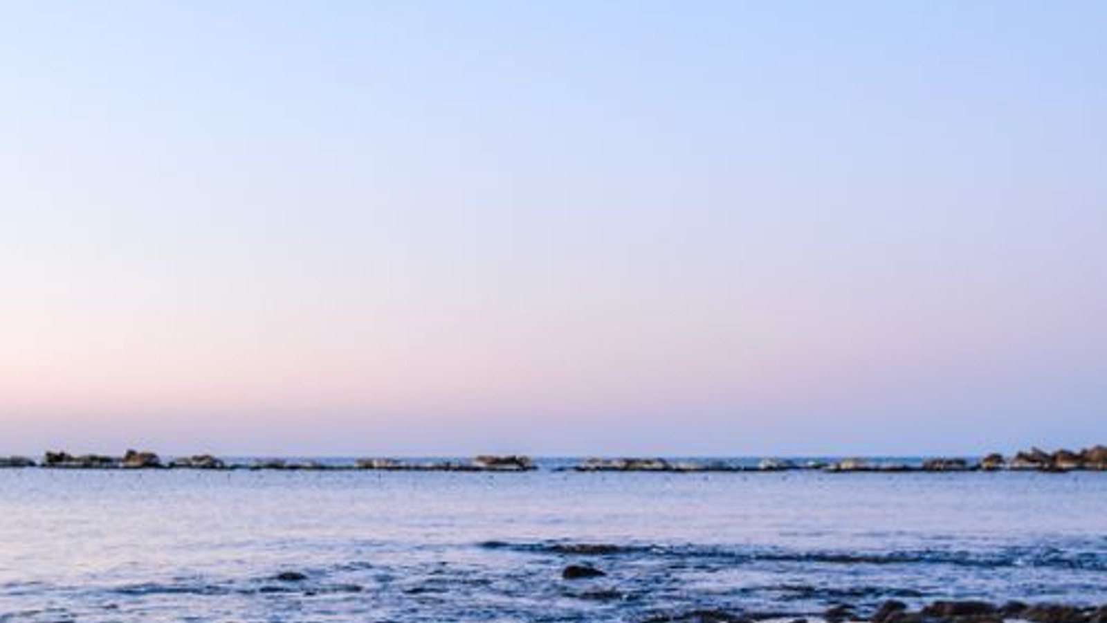 Gentle sea waves under a pale morning sky