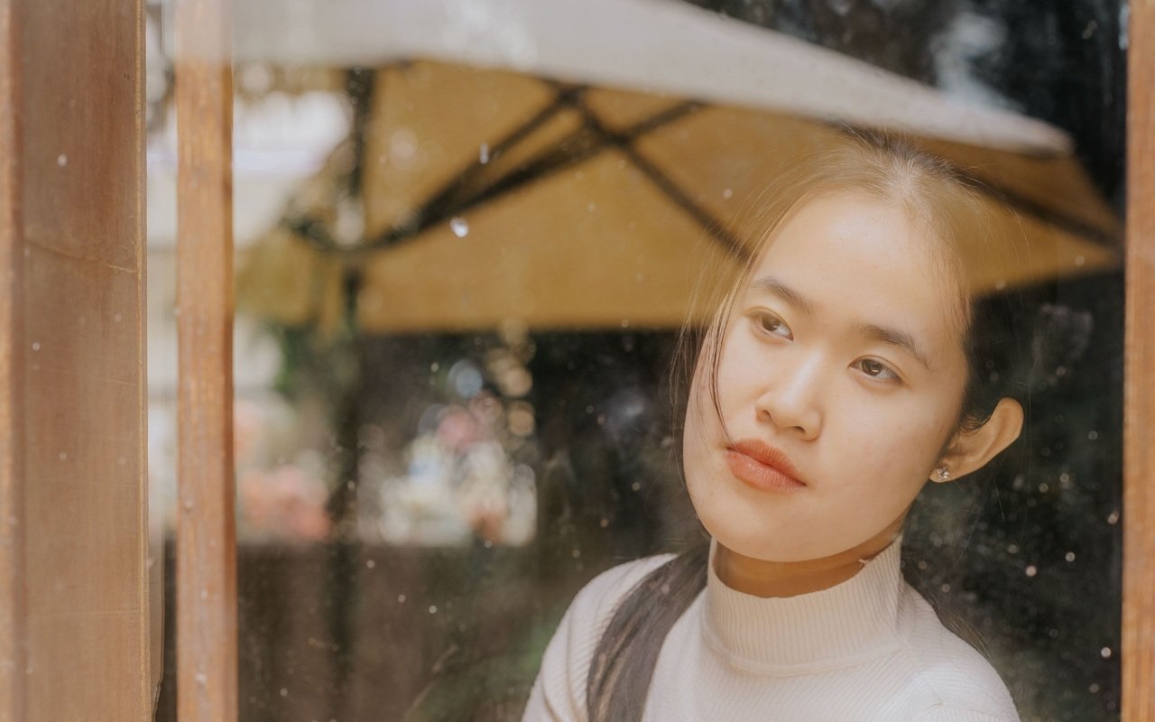 Woman seated beside an open window in natural light