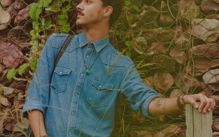 Man standing beside a stone wall and greenery