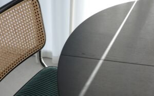 A chair beside a round table in soft window light