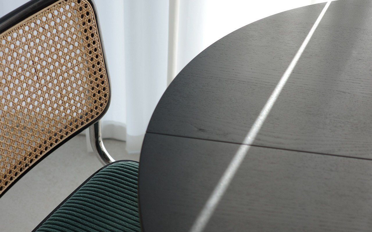 A chair beside a round table in soft window light