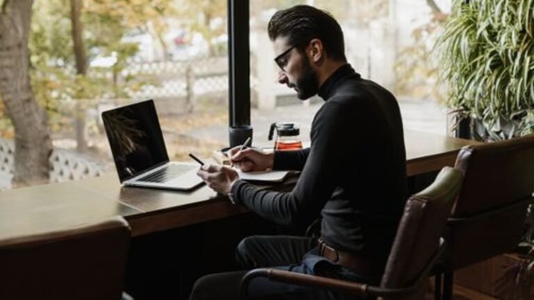 A person working at a laptop beside a cafe window
