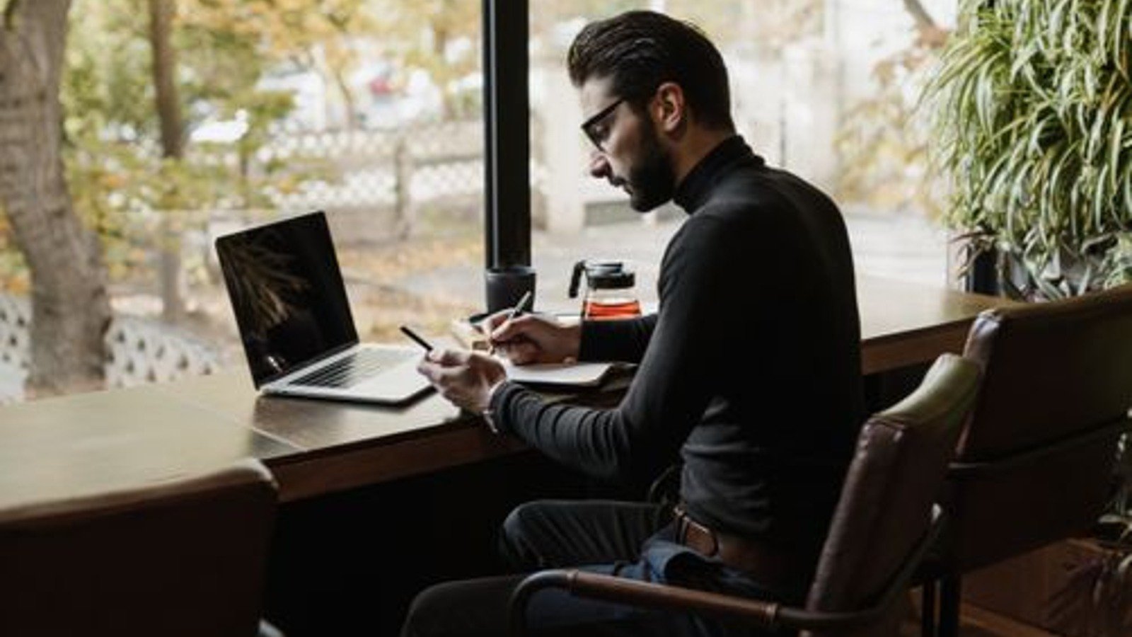 A person working at a laptop beside a cafe window