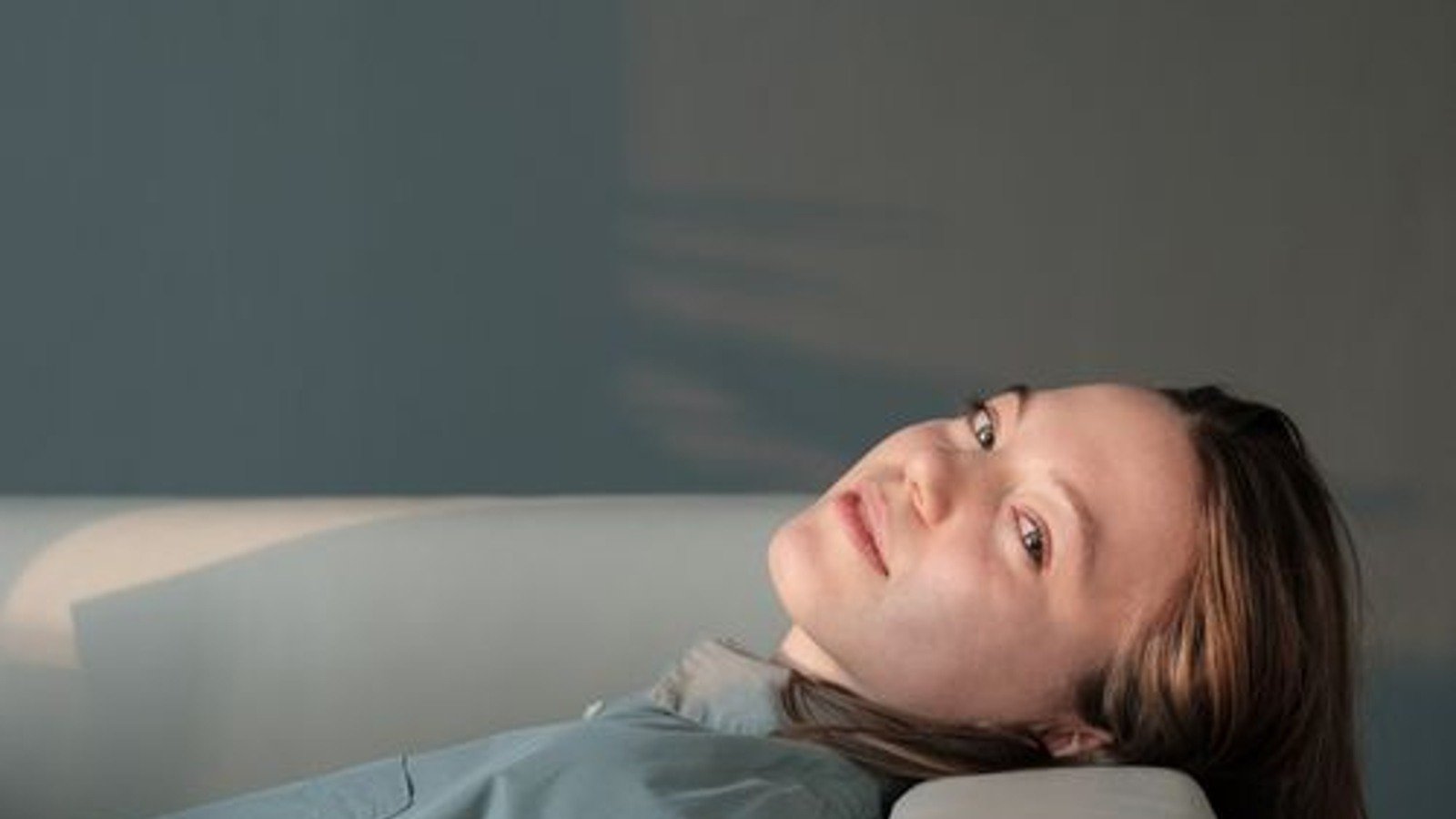 A person resting on a sofa in soft daylight