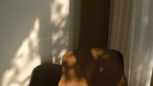 An empty wooden chair beside a curtain in natural light