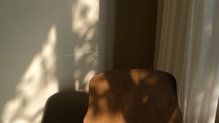An empty wooden chair beside a curtain in natural light