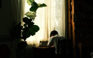 Person sitting at a table beside a sunlit window