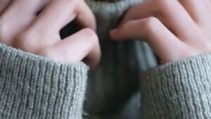 Hands resting against the edge of a soft grey sweater