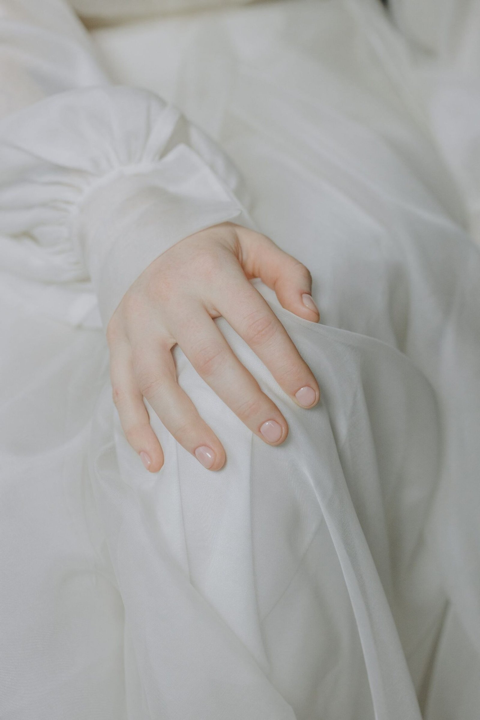 Hand resting on a knee in soft white fabric