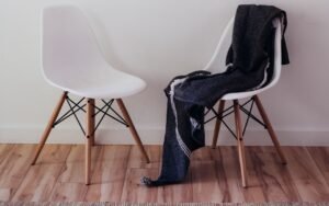 Two white chairs beside a wall, one draped with a dark blanket
