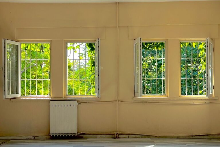 Sunlit empty room with open windows and a wooden floor