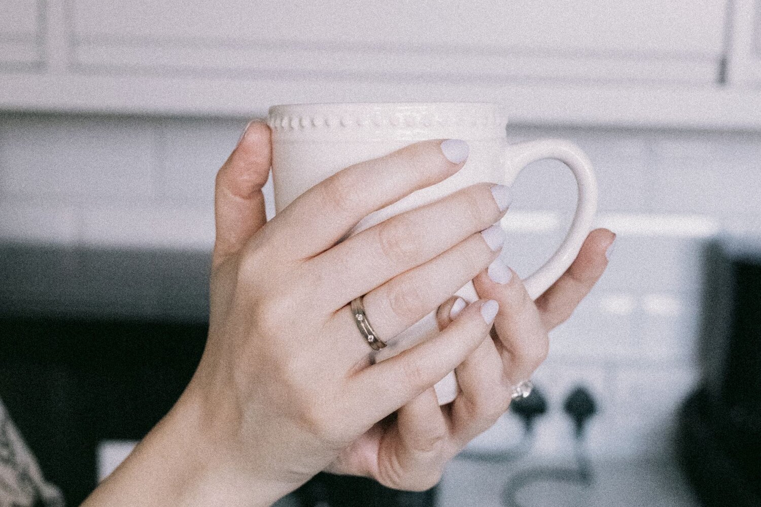 Hands holding a warm mug in a quiet kitchen