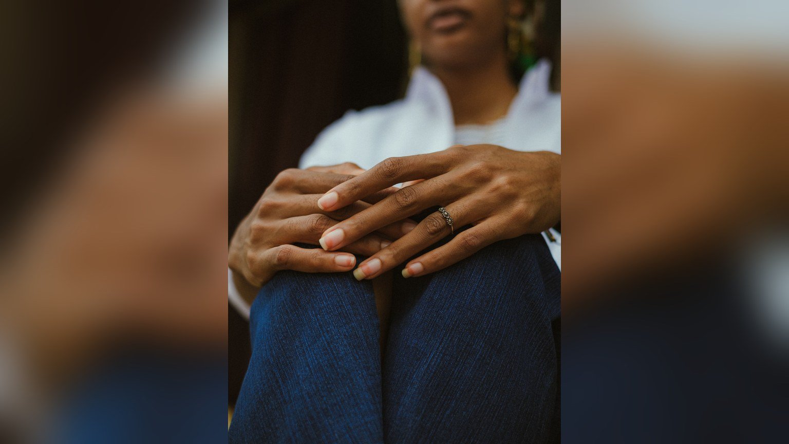 A woman's hands resting on her lap with a ring on one finger