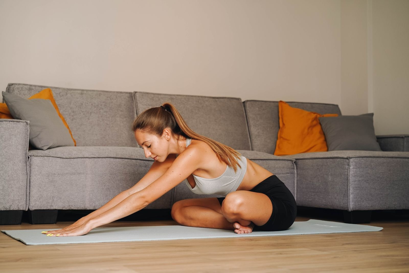 A woman stretching on a yoga mat in a living room