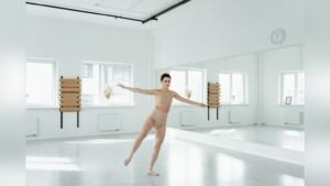 A young woman in activewear mid-movement in a bright dance studio