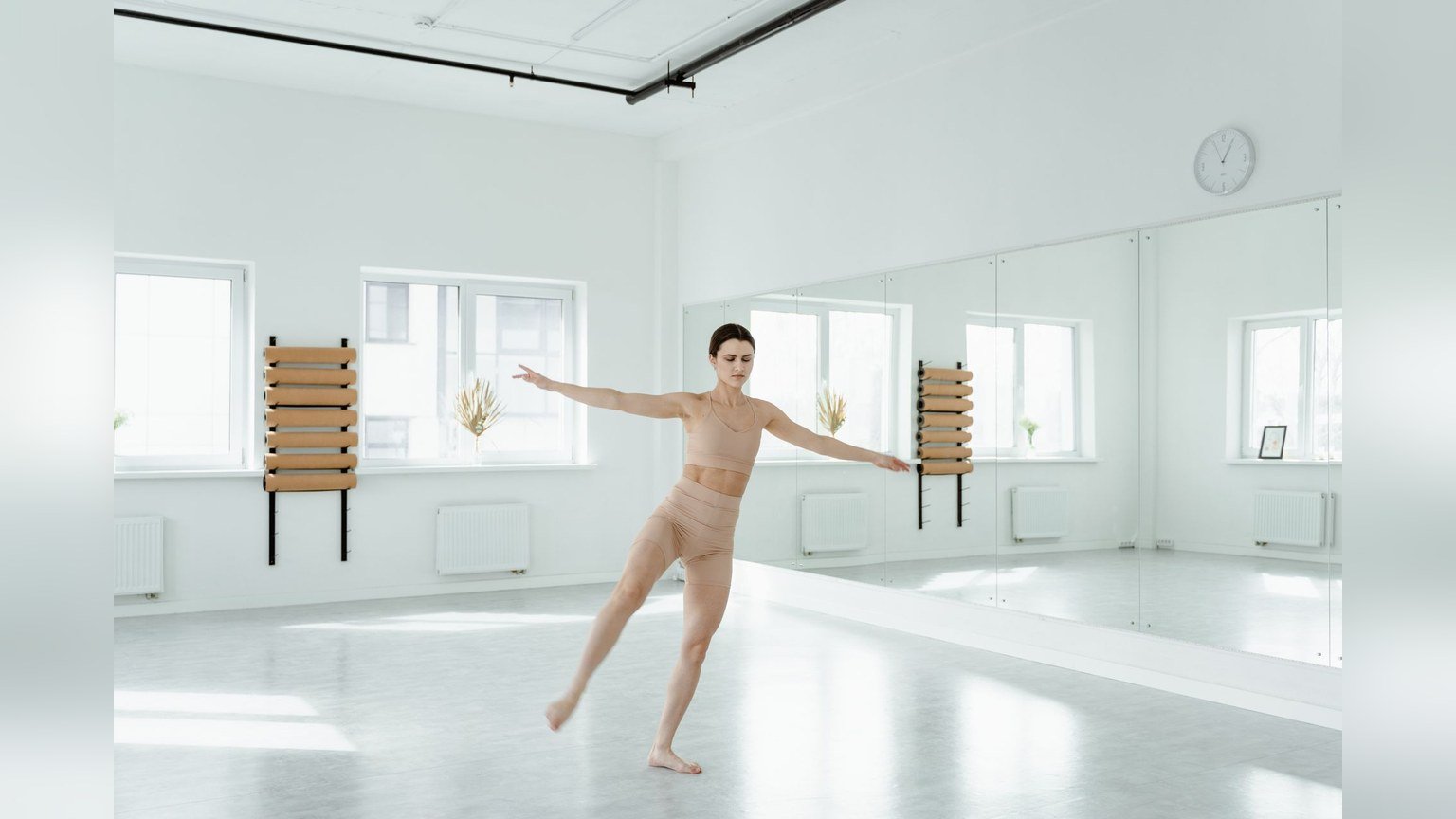 A young woman in activewear mid-movement in a bright dance studio
