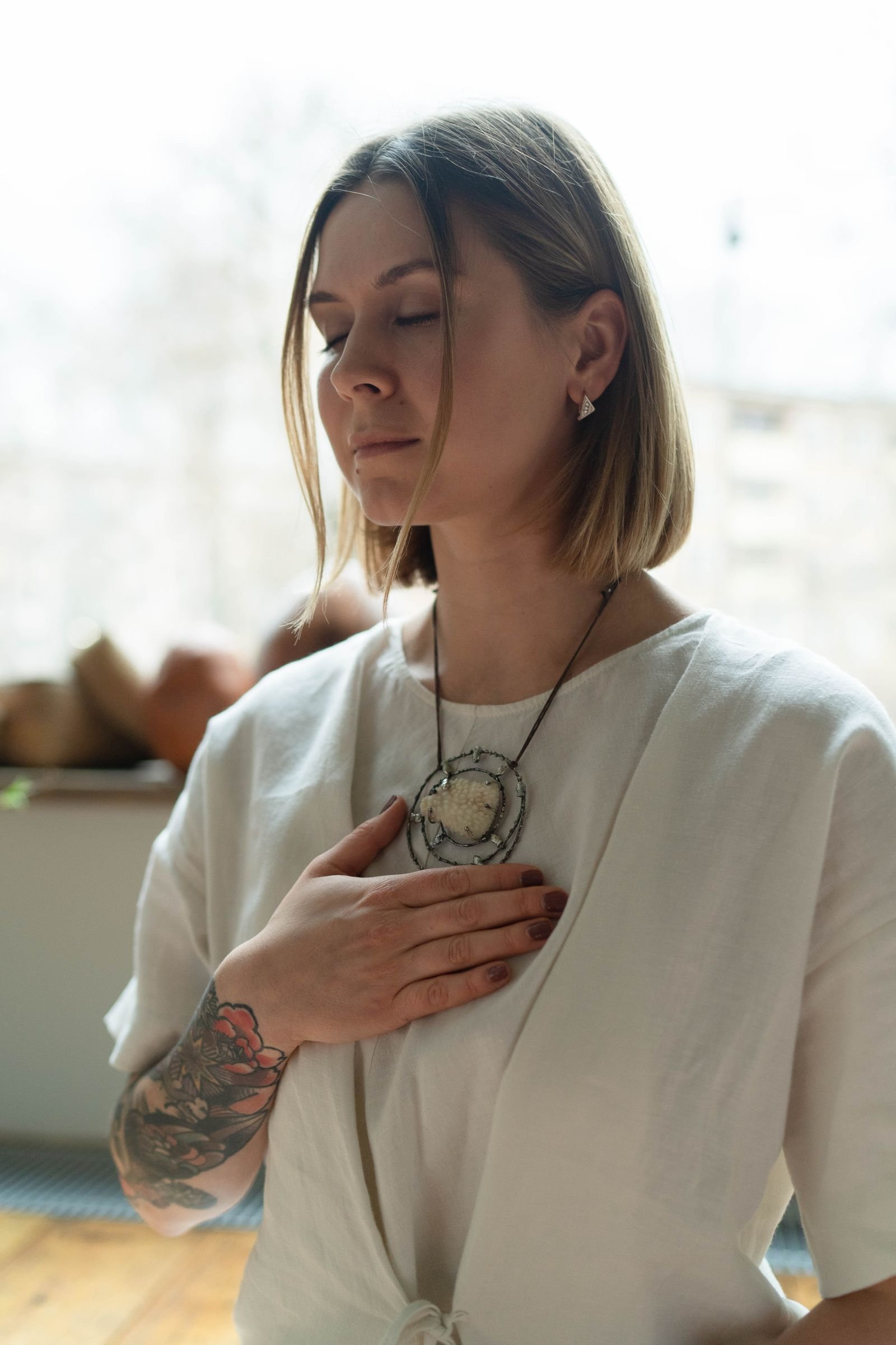 A woman with closed eyes resting her hands on her chest in a calm moment